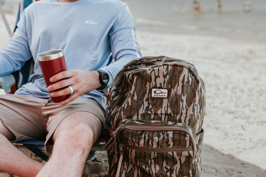 Person on beach with Limited Edition Throwback 80 Backpack, featuring rugged canvas and suede bottom, ideal for durable use. Limited stock.