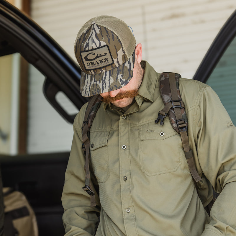 A man wearing a Traveler's Solid Dobby Button-Down Long Sleeve Shirt with hidden collar, chest pockets, and split tail hem. Ideal for outdoor adventures.