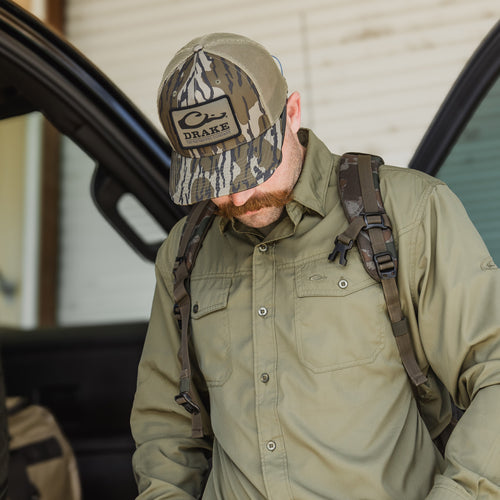 A man wearing a Traveler's Solid Dobby Button-Down Long Sleeve Shirt with hidden collar, chest pockets, and split tail hem. Ideal for outdoor adventures.