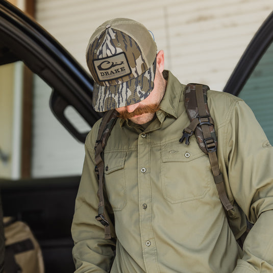 A man wearing a Traveler's Solid Dobby Button-Down Long Sleeve Shirt with hidden collar, chest pockets, and split tail hem. Ideal for outdoor adventures.