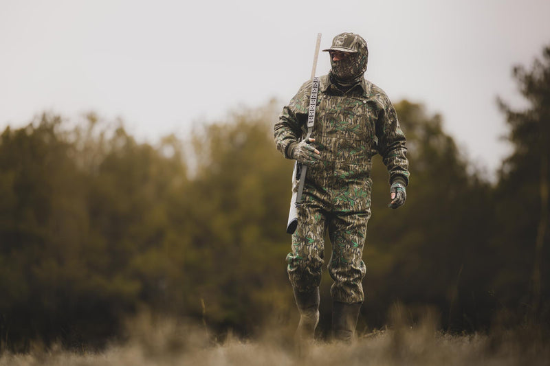 Throwback 80 Field Bib in camouflage, featuring durable cotton twill, reinforced knees, and antique brass details; ideal for tough outdoor activities.
