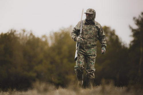 Throwback 80 Field Bib in camouflage, featuring durable cotton twill, reinforced knees, and antique brass details; ideal for tough outdoor activities.