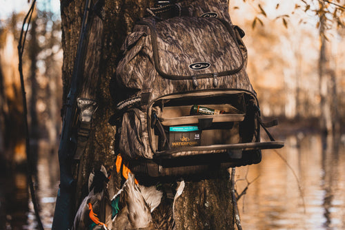 Tree Hugger Timber Pack with camo pattern, open to show Waterfowl shotgun shells, shotgun, and harvested ducks, demonstrating its rugged design and ample hunter storage features.