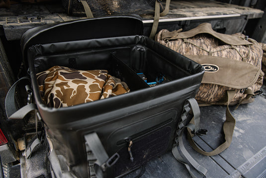 HND Carry All Collapsible Storage Bag on pickup tailgate, featuring camo items inside, ideal for versatile, weatherproof storage and transport of hunting gear.