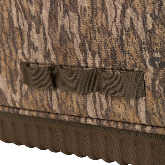 Close-up of the Tree Hugger Timber Pack, showcasing camouflage fabric, MOLLE-style webbing, and a molded, ribbed waterproof bottom for durability.