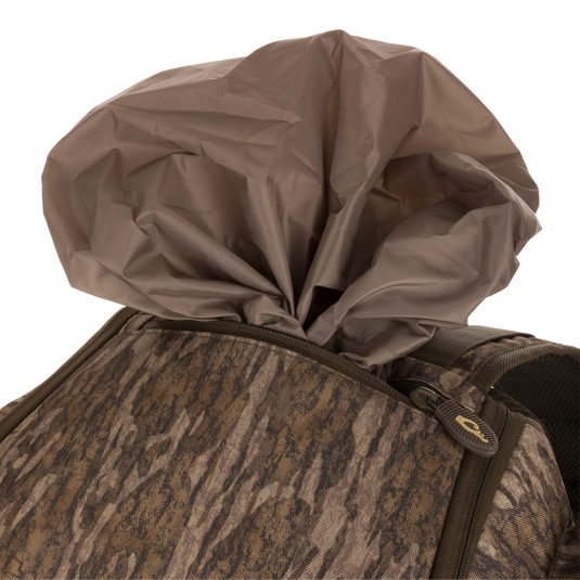 Camouflage-patterned Tree Hugger Timber Pack with partially exposed brown rain cover, showcasing rugged construction, multiple pockets, and ergonomic design for hunting gear organization.
