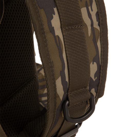 Close-up of Tree Hugger Timber Day Pack's camo-patterned shoulder strap, featuring padded mesh backing, heavy nylon webbing, and plastic D-ring for attachment.