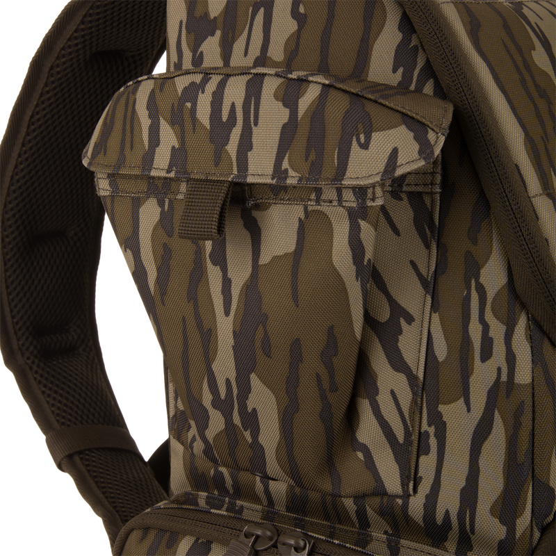 Tree Hugger Timber Day Pack close-up, showing camouflage pattern, front pocket with flap, padded shoulder strap, and zipper pull from lower compartment for outdoor gear access.