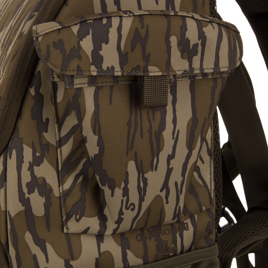 Tree Hugger Timber Day Pack close-up showing camouflage pattern, front pouch with flap, shoulder strap, and mesh backpad, highlighting its rugged, weather-resistant design for hunting excursions.