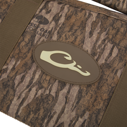 Migrator Gun Case close-up: camo-patterned fabric with olive-green straps and a brown C logo, highlighting durable, waterproof design for reliable firearm protection.