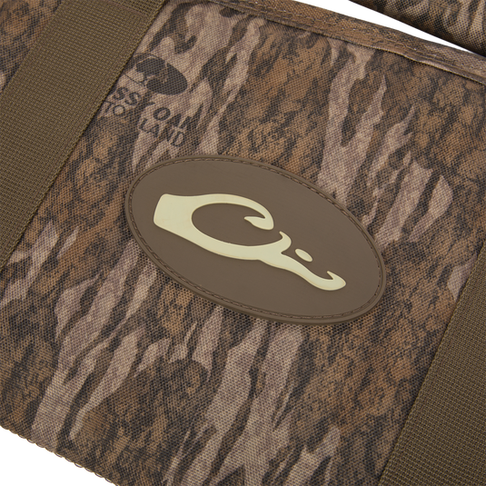 Migrator Gun Case close-up: camo-patterned fabric with olive-green straps and a brown C logo, highlighting durable, waterproof design for reliable firearm protection.