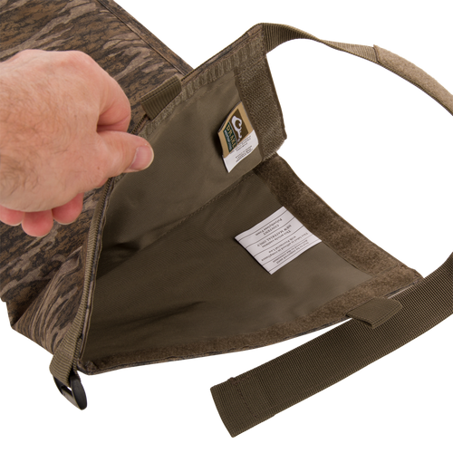 The Migrator Gun Case opened, revealing an empty olive-green interior, camo-patterned exterior, and webbing shoulder strap, emphasizing its durable, waterproof design for professional gear protection.