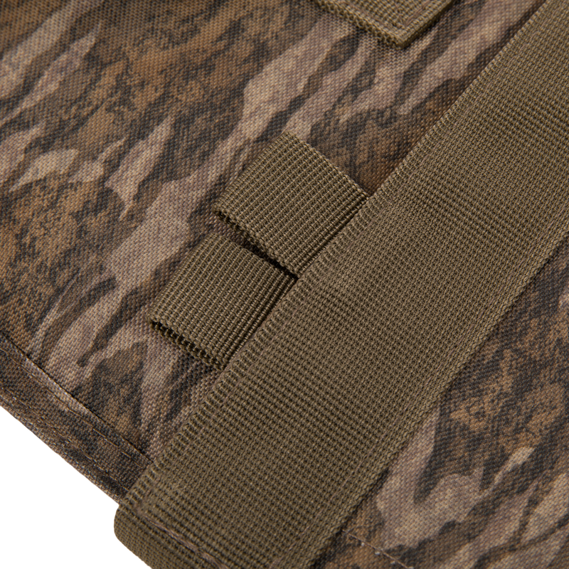 The Migrator Gun Case features camouflage fabric with olive-drab nylon webbing, showcasing MOLLE-style attachment points, ideal for durable, waterproof firearm protection.