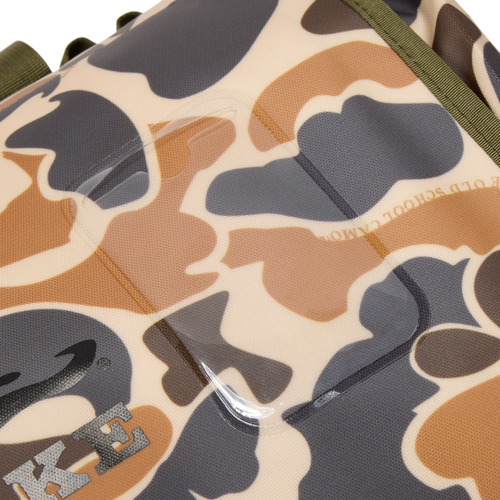 Close-up of Waterproof Duffel Bag's camouflage fabric, showcasing part of Nike swoosh, olive-green webbing, and clear ID tag holder stitched into material.