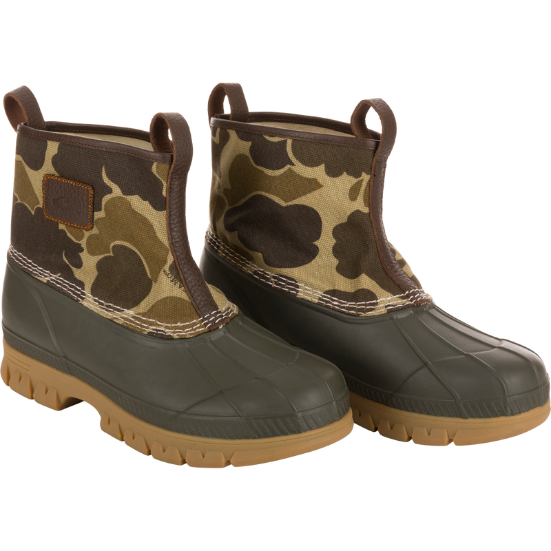 Throwback 80 Waxed Canvas Slip On Duck Boot with camo-patterned canvas, olive green rubber lower, brown trim, tan lugged outsole; features waterproofing and enhanced durability.