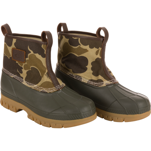 Throwback 80 Waxed Canvas Slip On Duck Boot with camo-patterned canvas, olive green rubber lower, brown trim, tan lugged outsole; features waterproofing and enhanced durability.