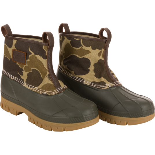 Throwback 80 Waxed Canvas Slip On Duck Boot with camo-patterned canvas, olive green rubber lower, brown trim, tan lugged outsole; features waterproofing and enhanced durability.