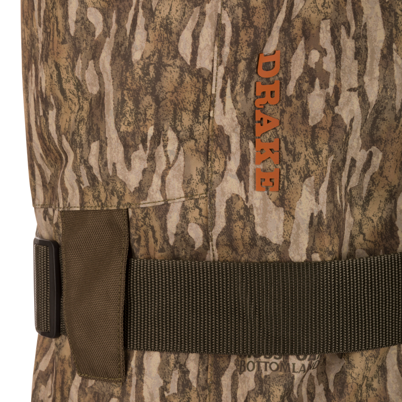 Close-up of Drake's Hardline Uninsulated Breathable Wader with camouflage pattern, featuring an adjustable belt, brand logo, and durable 3-layer waterproof fabric with front cargo pouch.