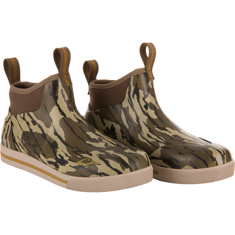 Camp Deck Boot with camouflage pattern, slip-on design, elastic side panels, and pull-tabs, featuring waterproof neoprene, moisture-wicking liner, and siped rubber outsole for wet conditions.