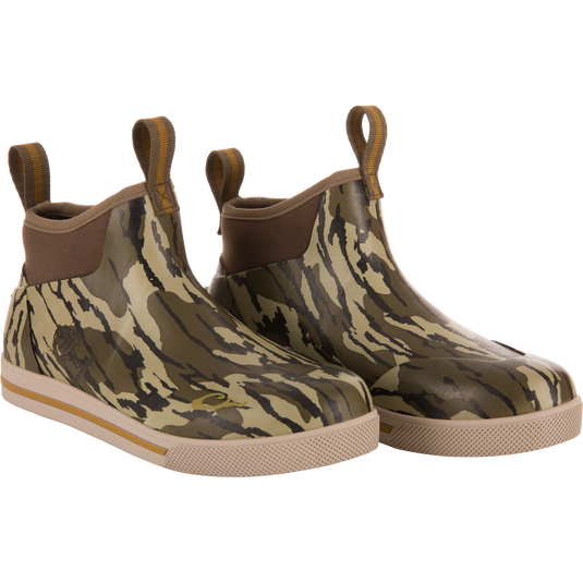 Camp Deck Boot with camouflage pattern, slip-on design, elastic side panels, and pull-tabs, featuring waterproof neoprene, moisture-wicking liner, and siped rubber outsole for wet conditions.