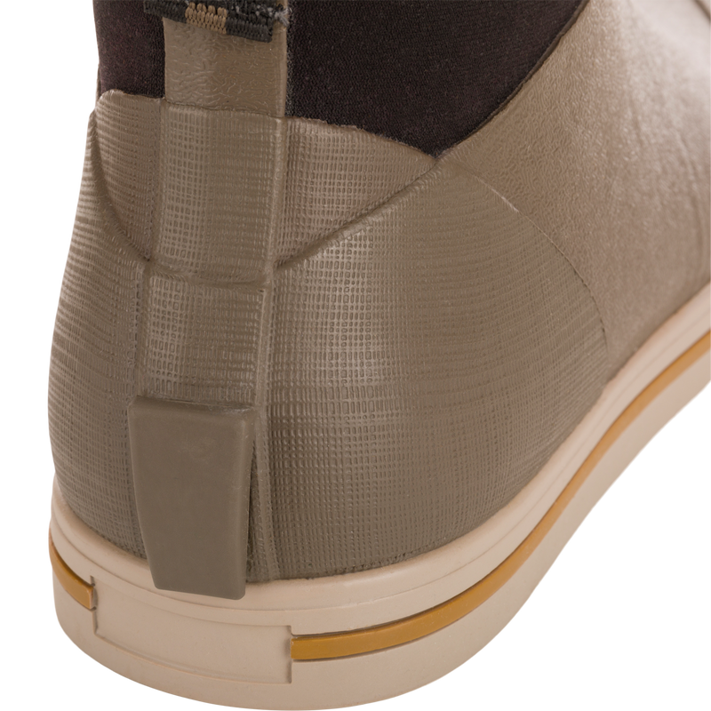 Close-up of Camp Deck Boot's heel, showcasing its olive-taupe waterproof rubber with textured grid, beige outsole, and ochre stripe, ideal for outdoor adventures.