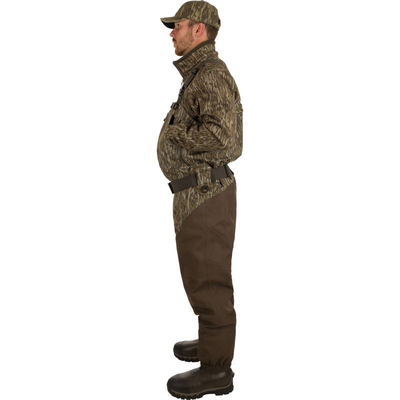 Uninsulated Guardian Elite HND Front Zip Waders: A man turned to the side wearing waders with Internal handwarmer pockets to keep your hands warm and protected on even the coldest days .
