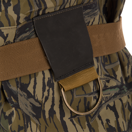 Close-up of BMF1600 Kevlar Wader with Primaloft, featuring tiger-stripe camo, brown belt, black patch, and tan loop with metal D-ring for enhanced hunting utility.