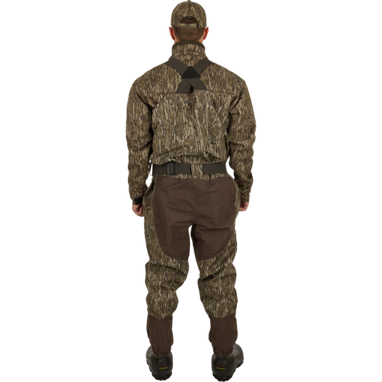A man in camouflage clothing wearing the Insulated Guardian Elite Vanguard Breathable Waders - Habitat, standing in a forest.