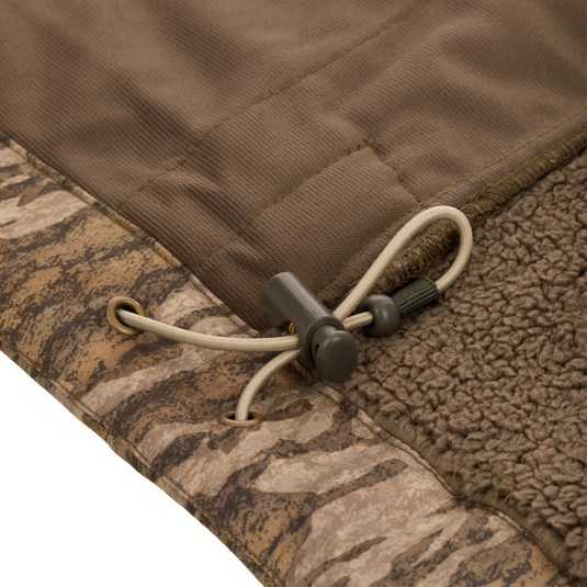 Midweight Nova Silencer Vest with Agion Active X2, featuring a camo-patterned shell, brown sherpa lining, and adjustable drawcord hem for warmth and functionality.