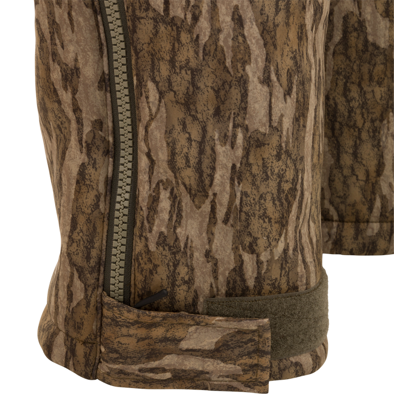 Close-up of Midweight Nova Silencer Bib's camo-patterned leg, featuring a zipper and Velcro strap, designed for warmth, breathability, and scent control in hunting environments.