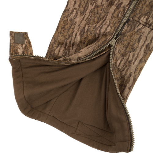 Close-up of the Midweight Nova Silencer Bib with Scent Control, showing the camo gaiter section, partially unzipped to reveal brown inner lining and adjustable Velcro tab.
