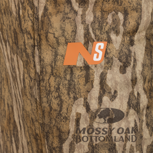 Close-up of Midweight Nova Silencer Pant with Scent Control in camo pattern, featuring NS logo and Mossy Oak Bottomland wordmark, highlighting anti-odor technology and mobility features.