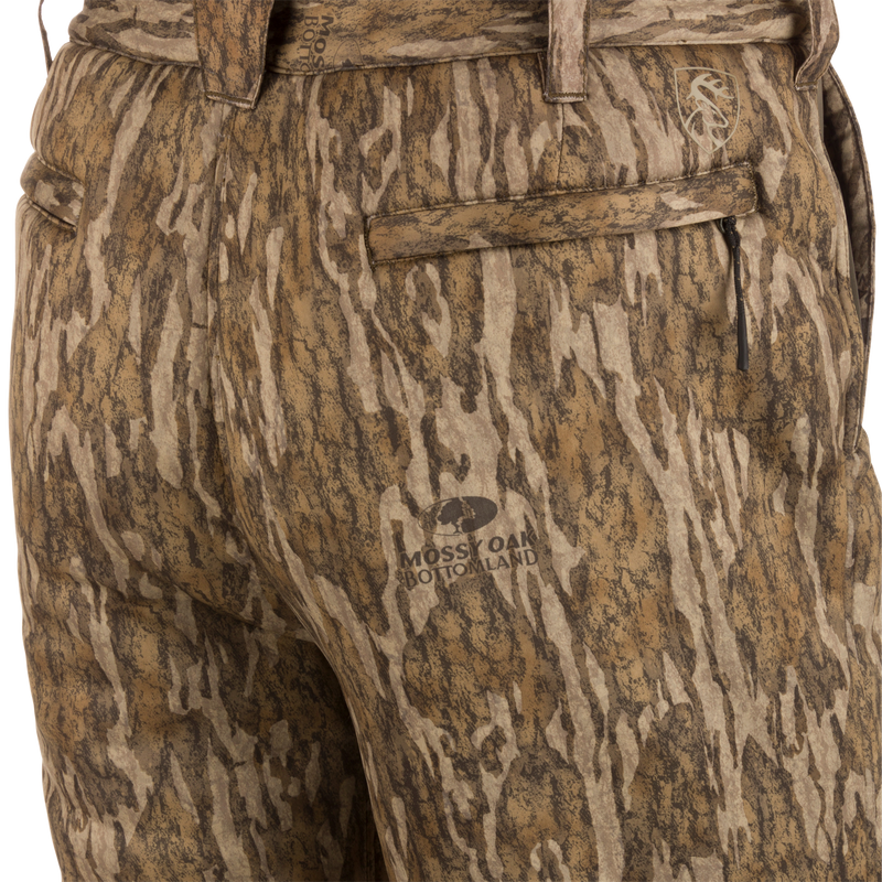 Close-up of Midweight Nova Silencer Pant with Scent Control in Mossy Oak Bottomland pattern, featuring zippered pockets, belt loops, and stretch waistband for mobility.