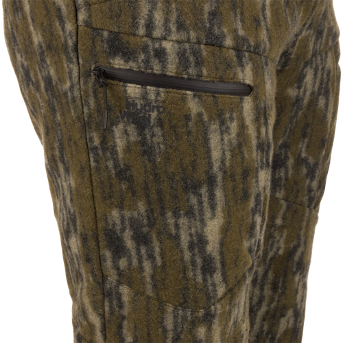 Midweight Hydrowool Softshell Pant with Scent Control close-up shows a camo wool-blend fabric with a waterproof zipper pocket and Hydro Wool logo, ideal for outdoor adventures.