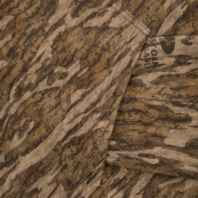 Close-up of Youth Non-Typical Performance Hoodie with Agion Active, showcasing Mossy Oak camo print, seams, and part of the label, emphasizing outdoor durability and flexibility.