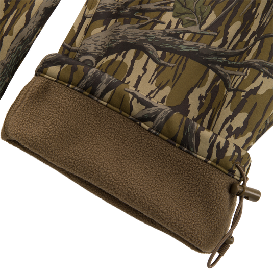 Close-up of Non-Typical Endurance Pant's hem, showing camouflage shell, brown fleece lining, and elastic drawcord with toggle for adjustable fit.