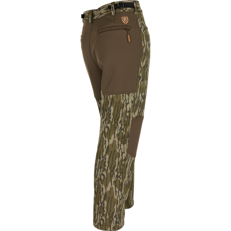 Youth Endurance Pant with camo pattern, solid brown stretch panels, built-in camo belt, zippered rear pocket, and reinforced knee patches, designed for active outdoor use.