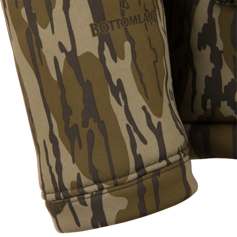 Close-up of BOTTOMLAND logo on Non-Typical Silencer Full Zip Hoodie cuff, showcasing camouflage design and high-quality polyester fleece for warmth and quietness.