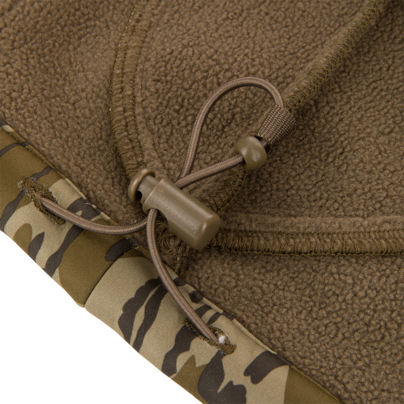 Close-up of Youth Endurance Full Zip Jacket with Hood, showing brown fleece hem with camouflage trim and elastic drawcord, highlighting durability for hunting activities.