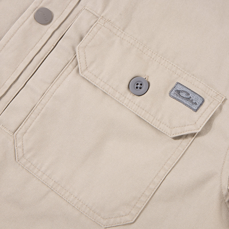 Close-up of the Drake Campfire Canvas Shirt Jac Hoodie, highlighting a flap-style chest pocket with a button, top-stitching, and a fabric logo tag.