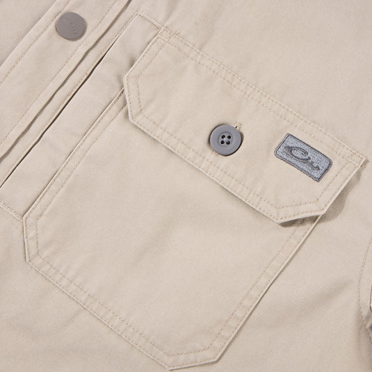 Close-up of the Drake Campfire Canvas Shirt Jac Hoodie, highlighting a flap-style chest pocket with a button, top-stitching, and a fabric logo tag.