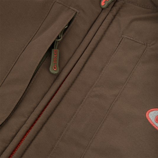 Close-up of the Drake Eqwader Vest's zipper, showcasing the waterproof, breathable fabric and secure chest pockets designed for hunting and outdoor activities.