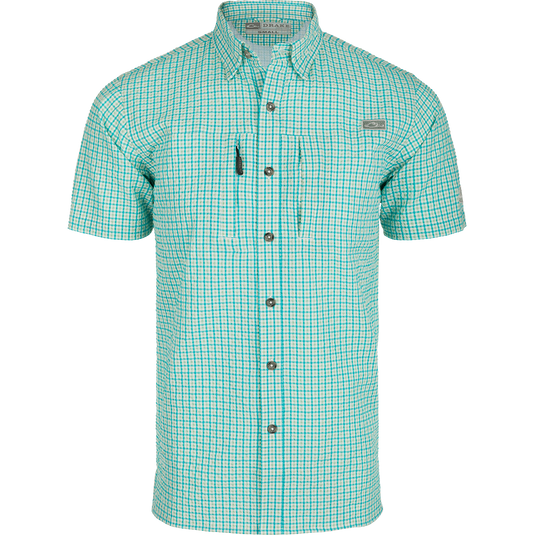 A Classic Seersucker Grid Check Shirt with a hidden button-down collar, zippered chest pocket, and Magnattach™ closure. Made from 76% Polyester and 24% Nylon, it offers UPF30 sun protection and moisture-wicking properties. Vented cape back and split tail hem provide ventilation and versatility. Perfect for hunting, fishing, or casual wear.