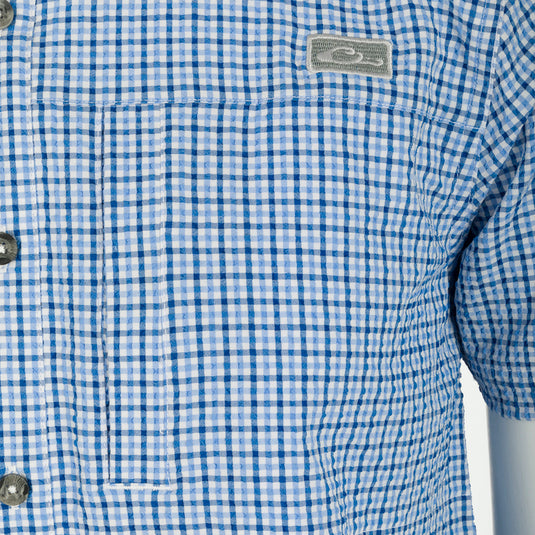A close-up of the Classic Seersucker Grid Check Shirt S/S, featuring a blue and white checkered pattern, hidden button-down collar, and zippered chest pocket.