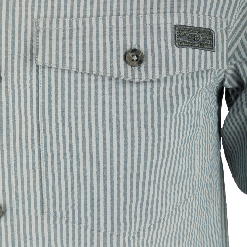 Close-up of the Frat Seersucker Striped Button-Down Short Sleeve Shirt, showcasing its vented cape back, hidden button-down collar, and button-through flap chest pocket.