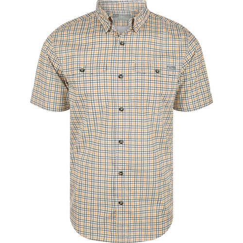 A white and orange plaid shirt with a hidden button-down collar, two button-through flap chest pockets, and a vented cape back. Made from lightweight performance fabric with UPF30 sun protection and moisture-wicking properties. Classic styling and technical features make the Frat Tattersall Shirt in a class of its own.