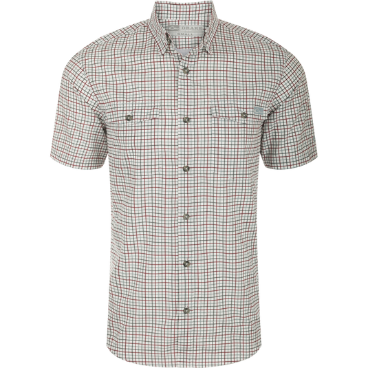 A close-up of the Drake Frat Tattersall Shirt, featuring a white and red plaid pattern. The lightweight performance fabric offers UPF30 sun protection, moisture-wicking, and quick-drying properties. With a classic fit and hidden button-down collar, it also includes two button-through flap chest pockets, a vented cape back, and a sculpted hem. The shirt even has a built-in sunglass wipe. Perfect for big game hunting, waterfowl hunting, turkey hunting, fishing, and casual wear.