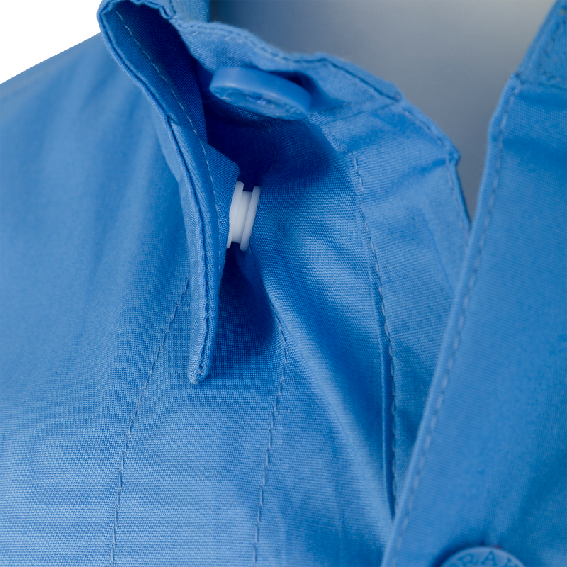 Close-up of the Wingshooter Trey Solid Short Sleeve Shirt, highlighting its button on blue fabric, with features like hidden button-down collar and vented back.