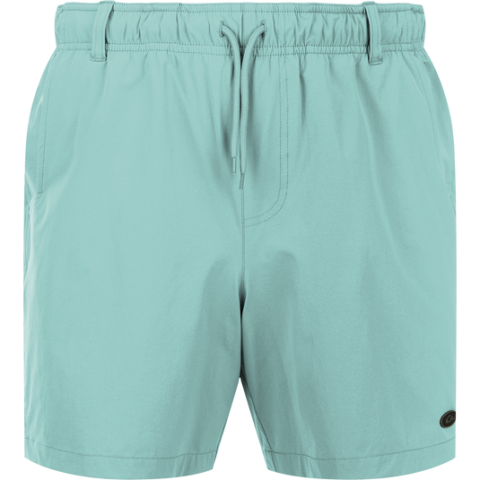 Dock Short 6" - A pair of light blue swim trunk shorts with a close-up of a zipper. Made from durable 90% Nylon/10% Spandex fabric with a water-resistant finish. Features elastic waist, belt loops, and front/back mesh pockets. Perfect for boat to dock transitions.