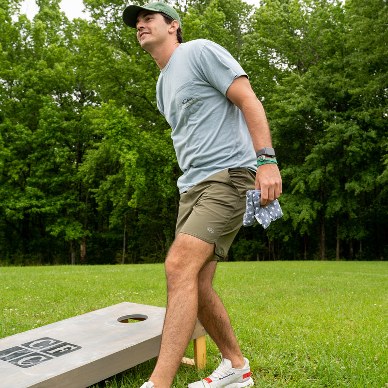 A man in Commando Lined Volley Short 9 plays outdoor sports on a grass field. Versatile, quick-drying, with 4-way stretch, moisture-wicking, and built-in liner.